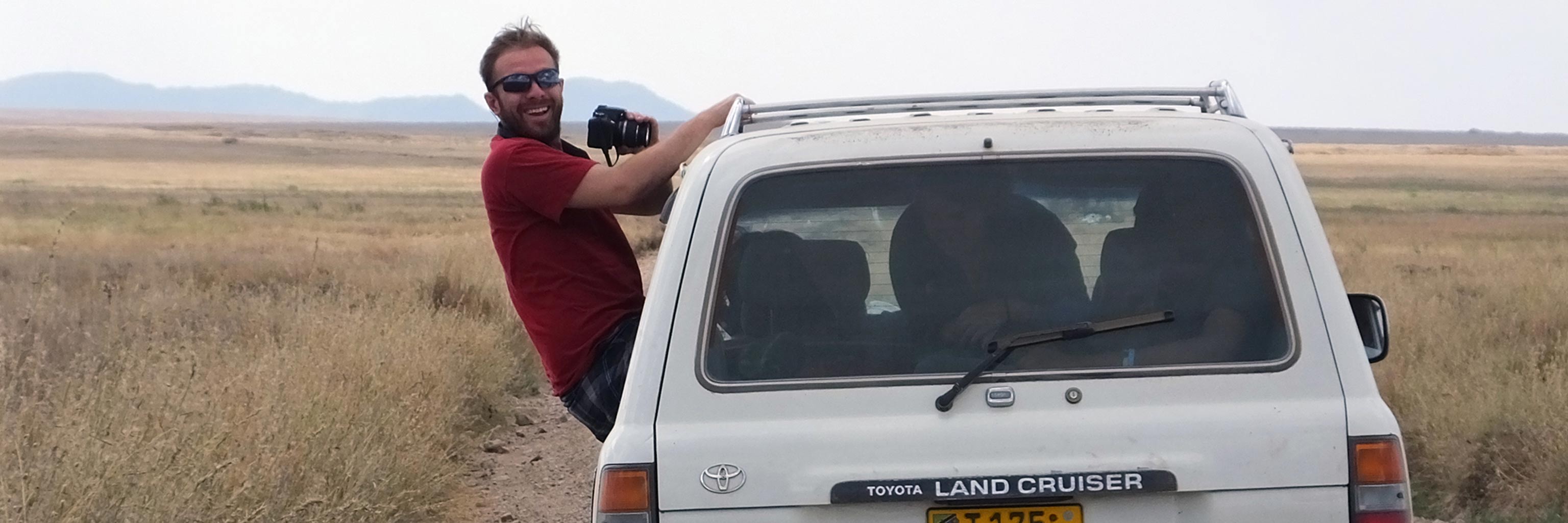 Student leaning out of a vehicle to take photos for field research