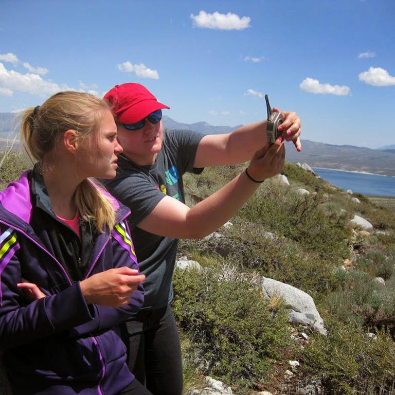 Two students using a compass for field research