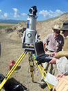 Geologists stand next to camera and instrumentation equipment outside